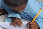 Young Nepalese schoolboy in a blue uniform leaning over his textbook